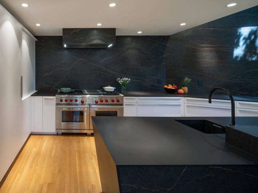 Angled Inalco porcelain island with undermount sink and matching full-height range wall, fabricated by Custom Touch Granite