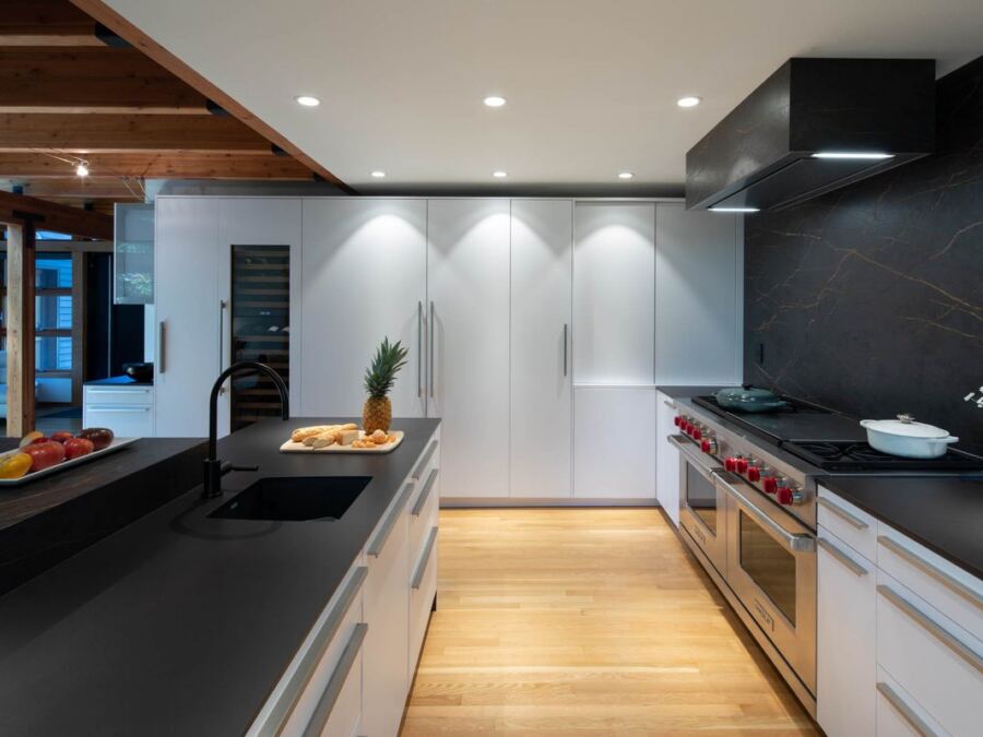 Inalco porcelain perimeter run past the range with a full-height slab backsplash, fabricated by Custom Touch Granite