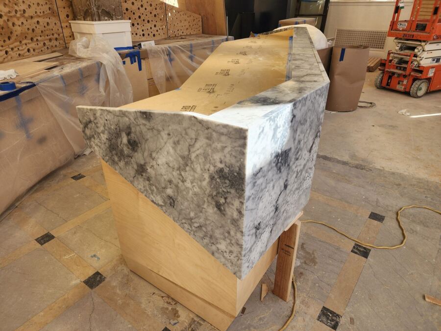 White and grey marble reception desk with a mitered waterfall end, fabricated and installed by Custom Touch Granite in the University District, Seattle WA