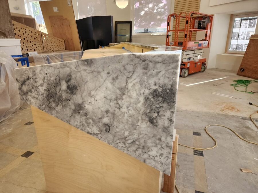 Full-length mitered marble front panel on a reception desk during installation, University District, Seattle WA